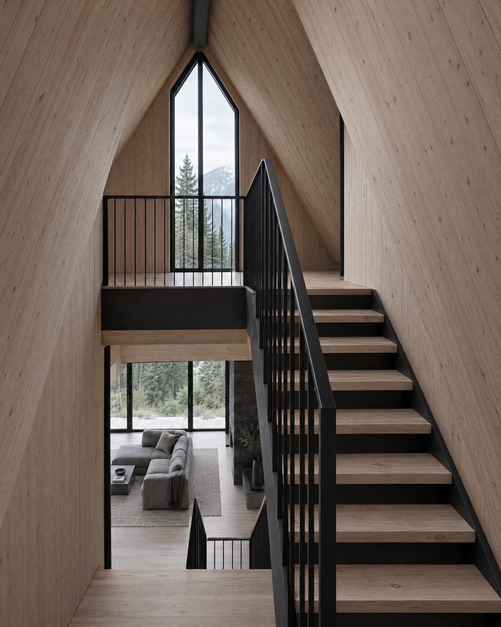 Stair core of The Three: a black steel stair with oak treads beside a larch wall, lit by a tall narrow window