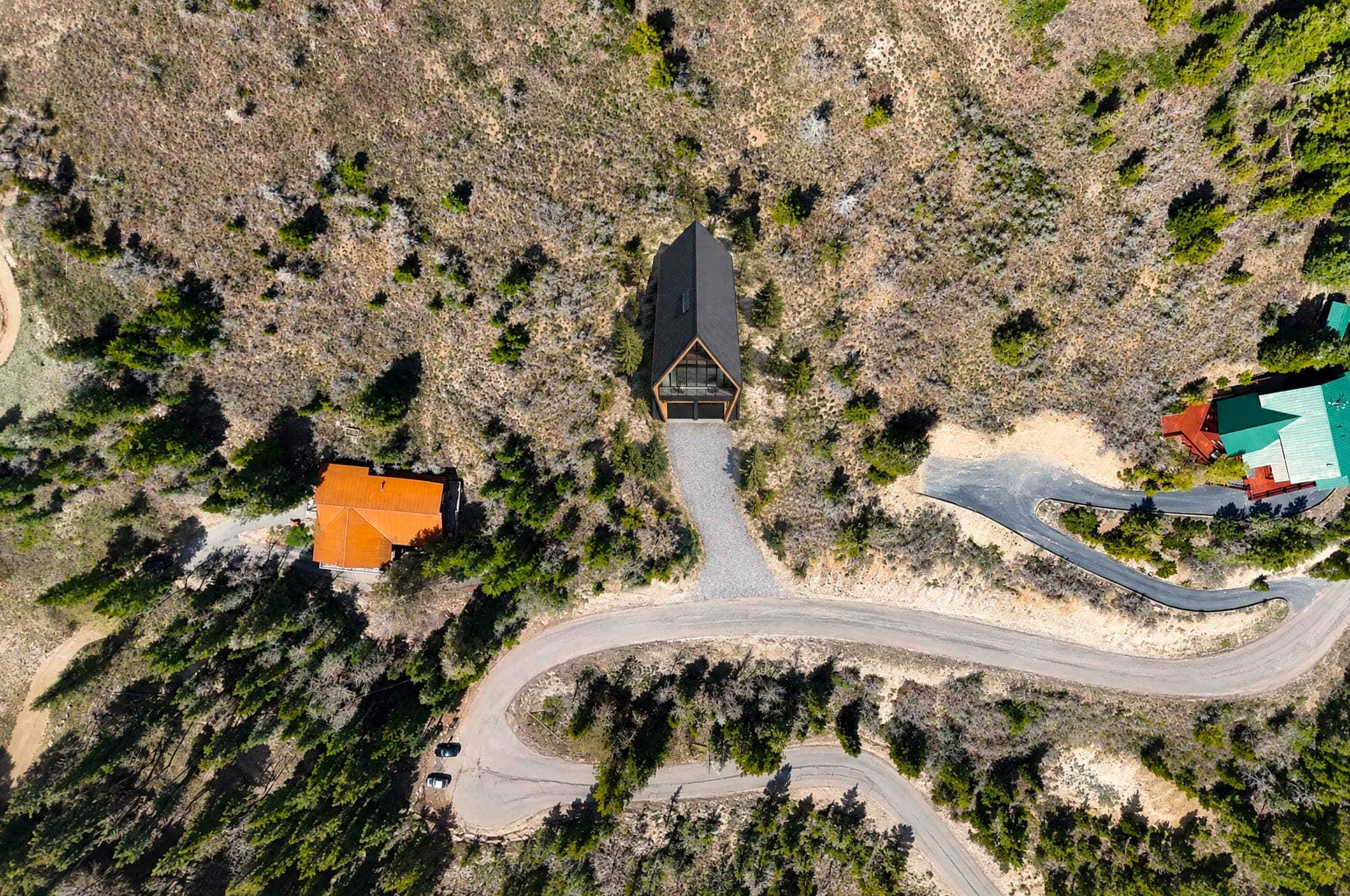 The lot at 655 Matterhorn Drive from directly above, with The Four's black roof among the trees beside the road loop